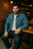 mężczyzna siedzący przy barze w jeansowej koszuli, białej koszulce i granatowych jeansach